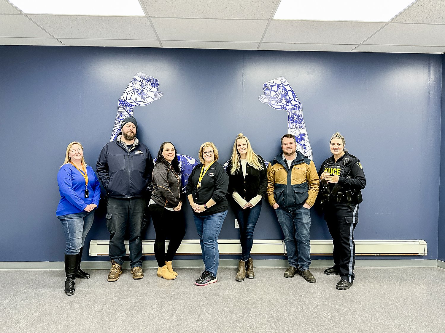 A group of people stand in front of a Strong Arms Decal that depicts different recreation activities. 